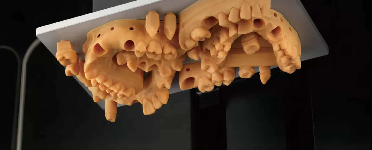 Orange printed dental arch models on a build platform